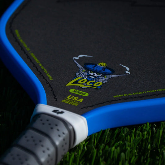 Close-up blue pickleball paddle edge and black playing surface with logo and grip
