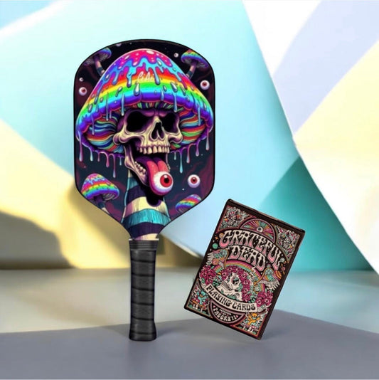 Pickleball paddle with colorful skull-and-mushroom face graphic and matching playing cards