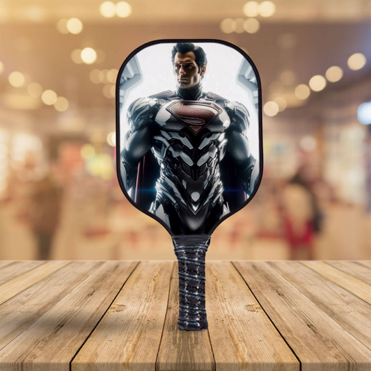 Pickleball paddle with Superman graphic on dark blue and black face, contoured handle