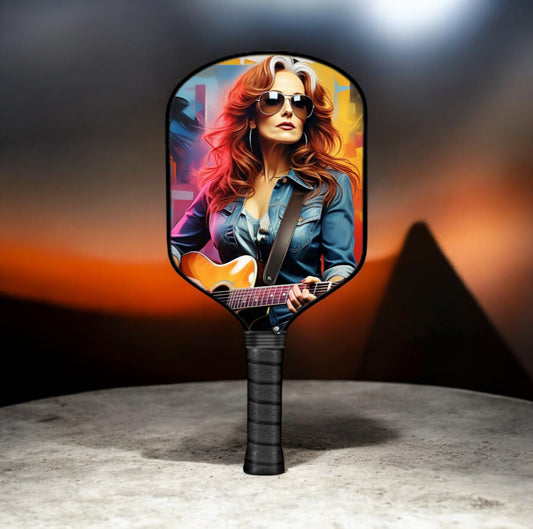 Pickleball paddle with black handle and round face featuring guitar portrait artwork