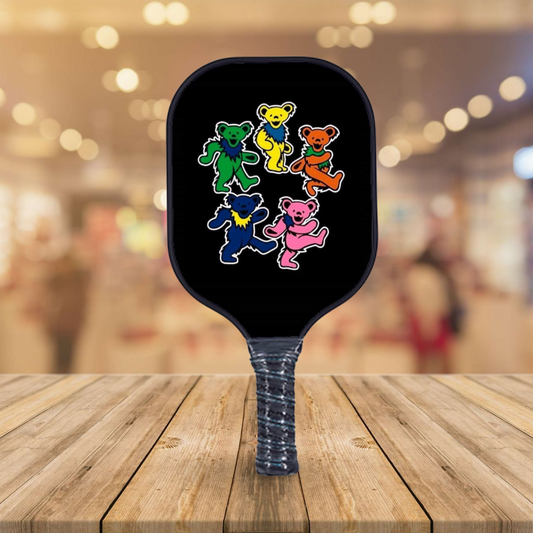 Pickleball paddle with black face and colorful dancing bears graphic, blue textured handle