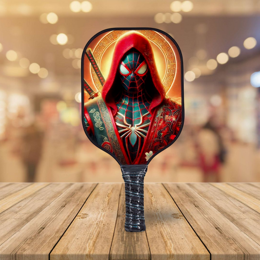 Pickleball paddle with red hooded masked spider graphic and dark patterned face