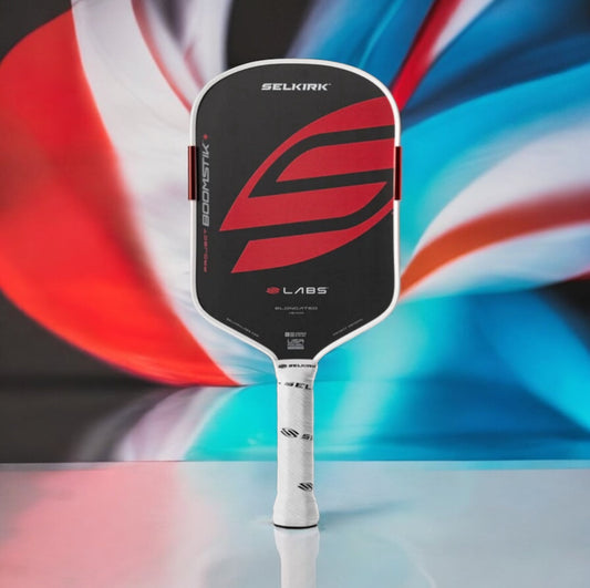 Elongated pickleball paddle with black face, red accent graphics, and white grip