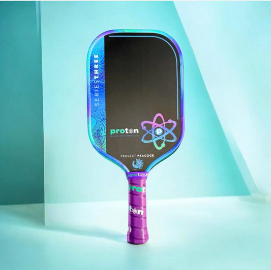 Elongated pickleball paddle with dark hitting surface, teal-to-blue frame, and purple handle
