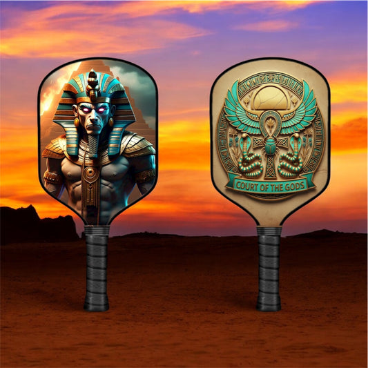 Pickleball paddle with teal-and-gold Egyptian god artwork faces, black grip handle