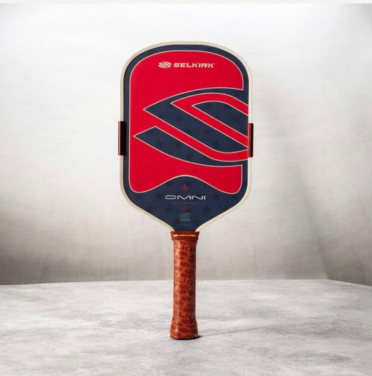 Selkirk OMNI pickleball paddle with red and navy face, textured orange grip handle