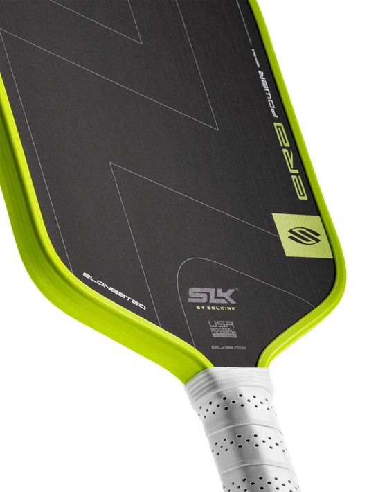 Elongated pickleball paddle close-up: black hitting surface with lime border and SLK logo.